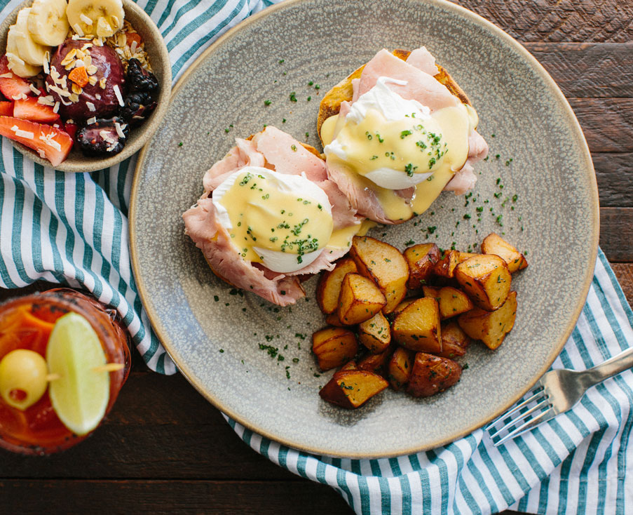 breakfast plate with potatoes, egg sandwich, acai bowl, and breakfast cocktail